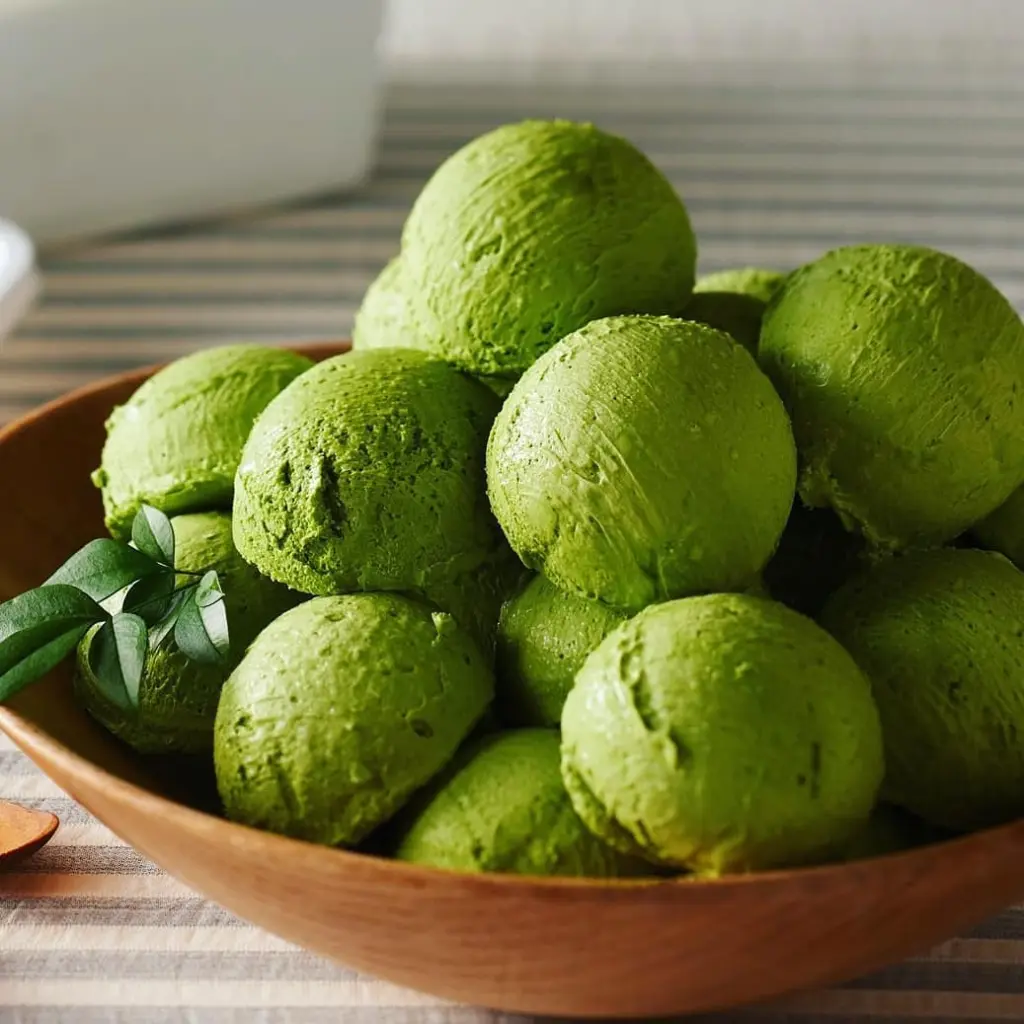 Bright green dessert scoops piled in a wooden bowl
