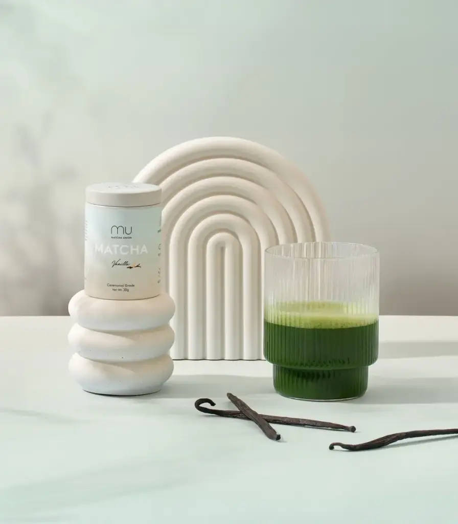 Matcha Union Vanilla Matcha tin beside a glass of green matcha and vanilla pods