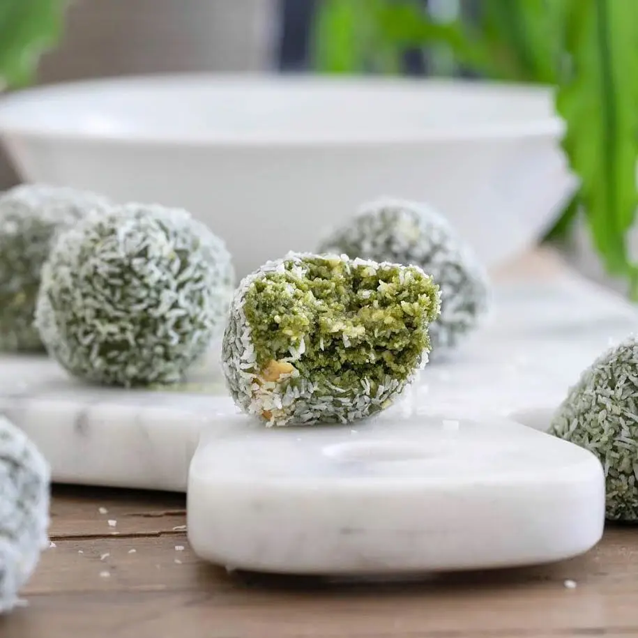 Green dessert bites coated in shredded coconut, with one cut open