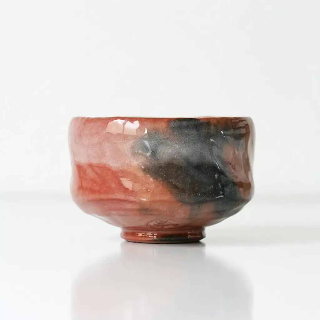 Rounded ceramic bowl with glossy red, pink, and dark gray glaze