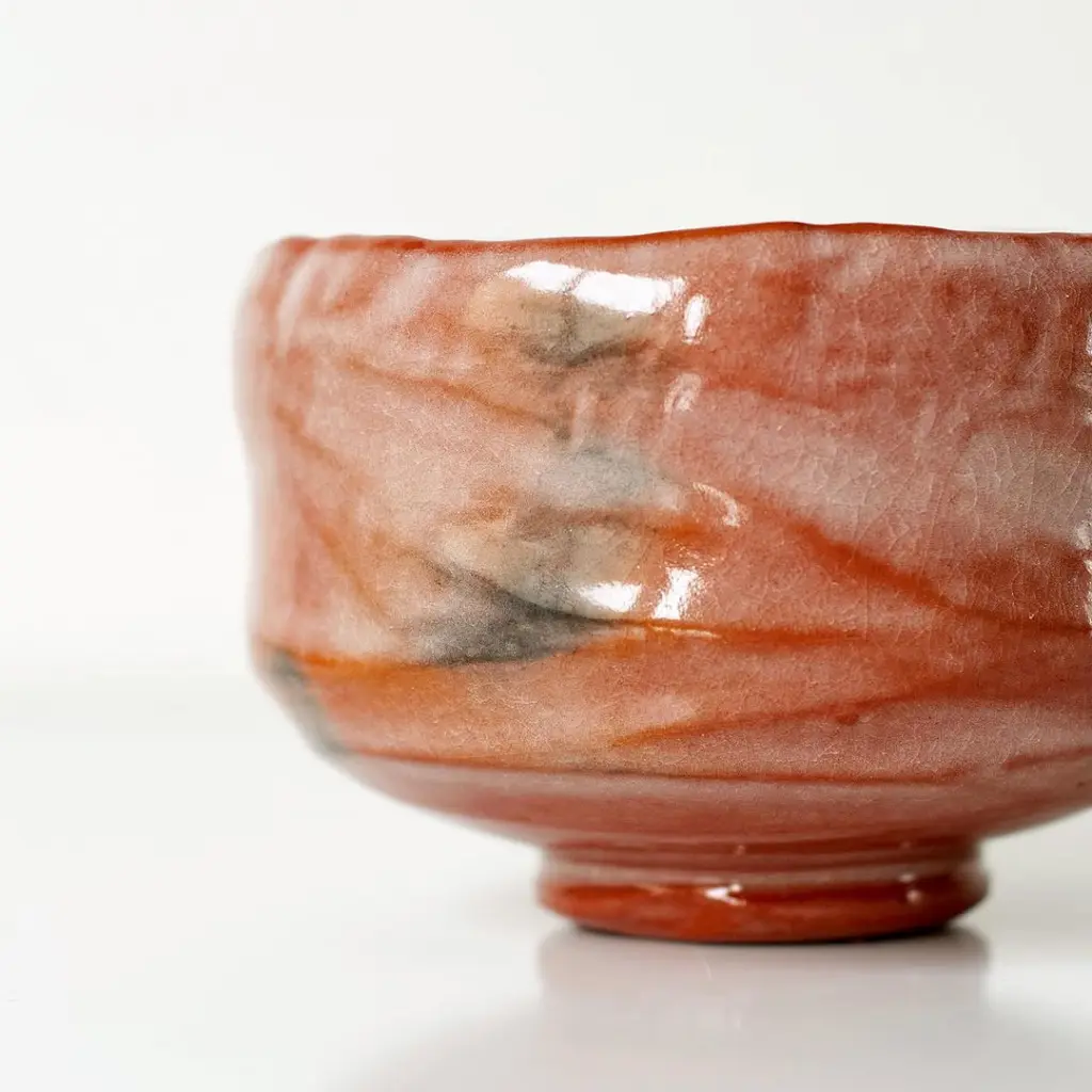Close-up of glossy red ceramic glaze with gray markings and fine crackling
