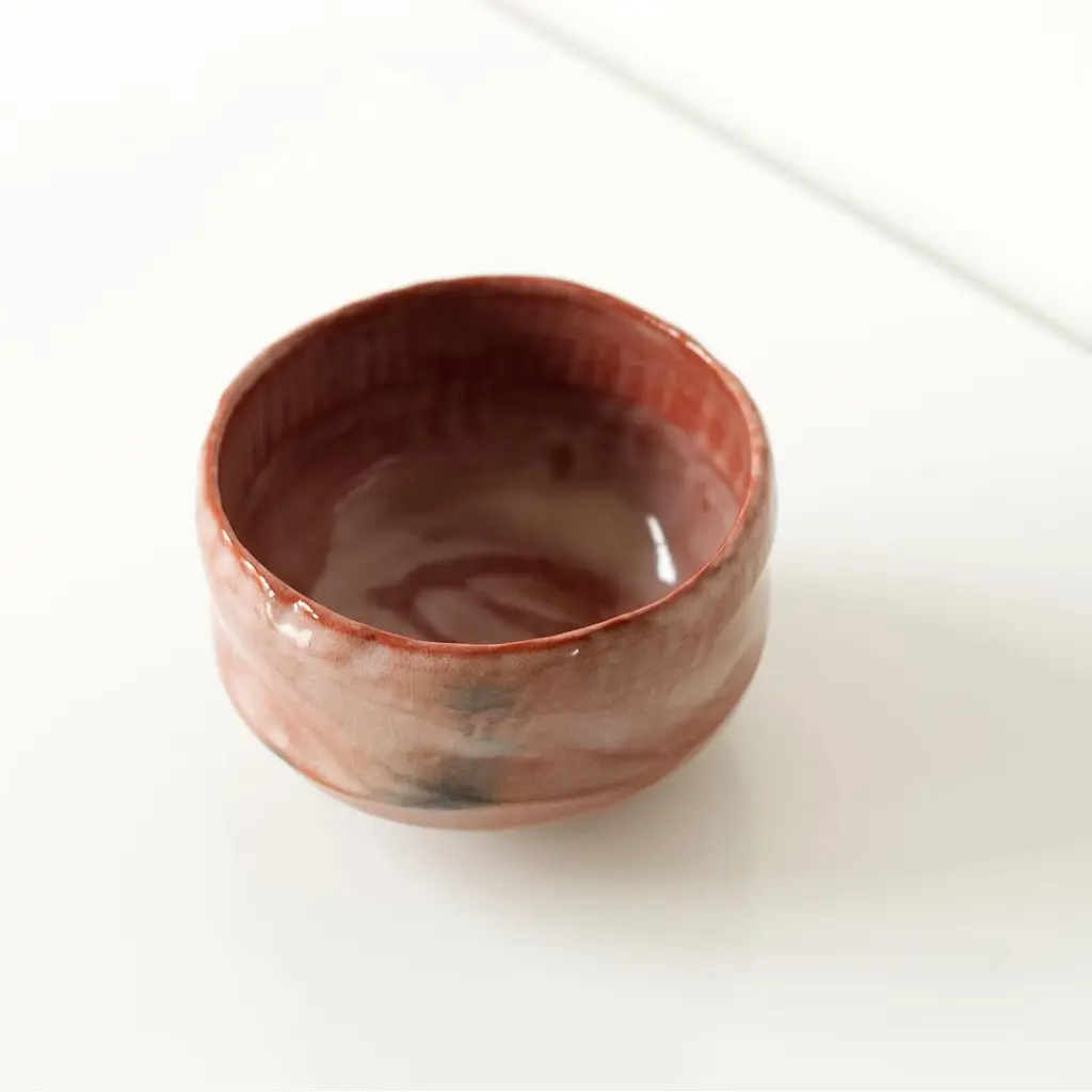 Top view of an empty red glazed ceramic bowl with an uneven rim