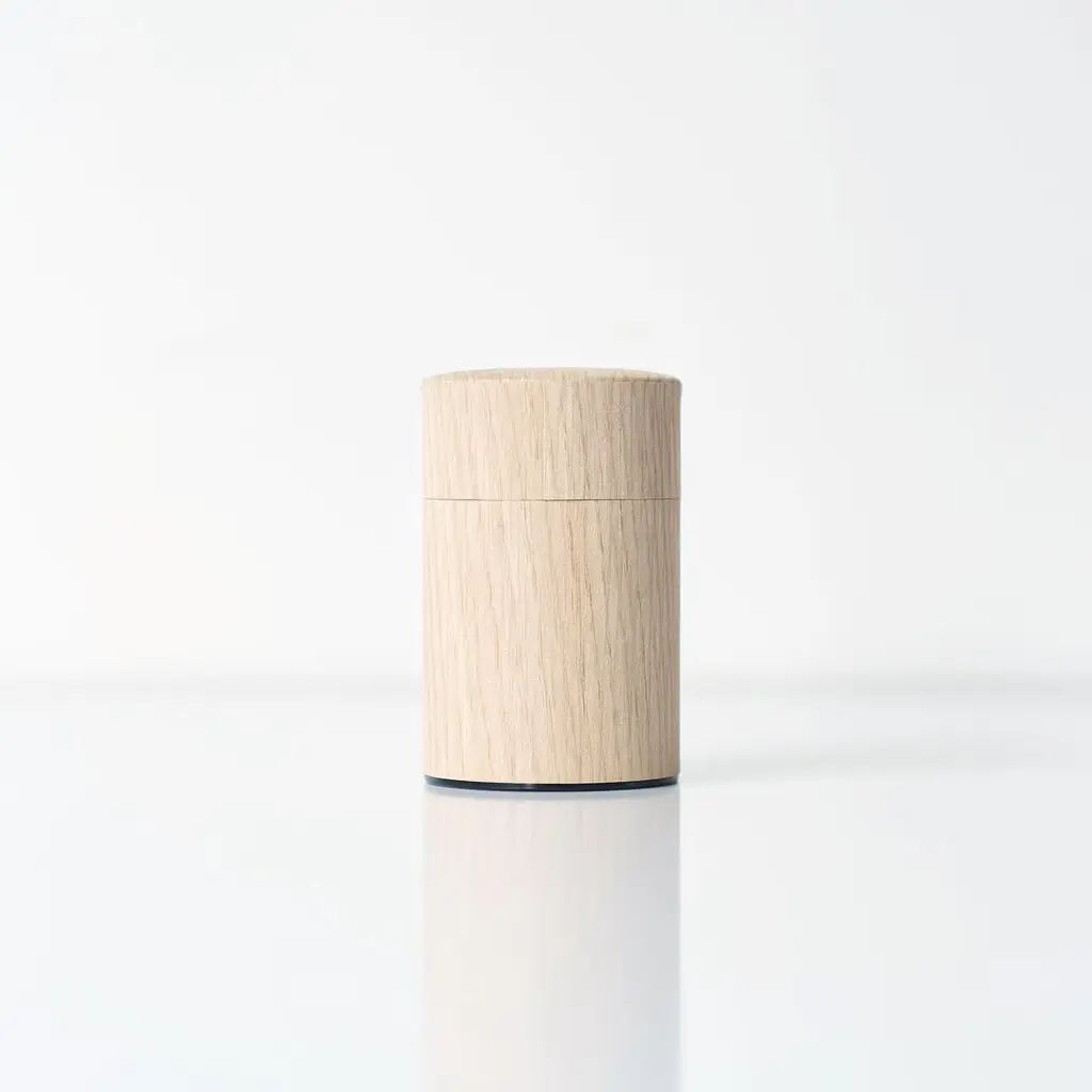 Closed cylindrical wooden container on a white surface